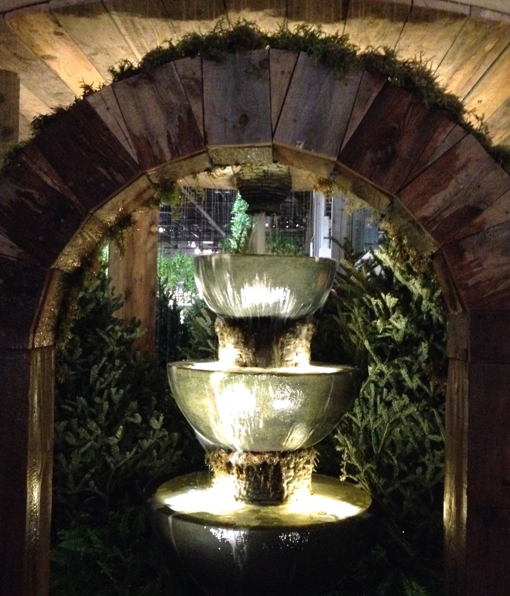 A wooden archway of recycled wood frames a water feature.