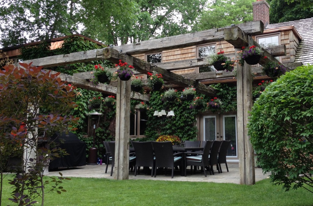 A large pergola overhangs a patio with dining area.