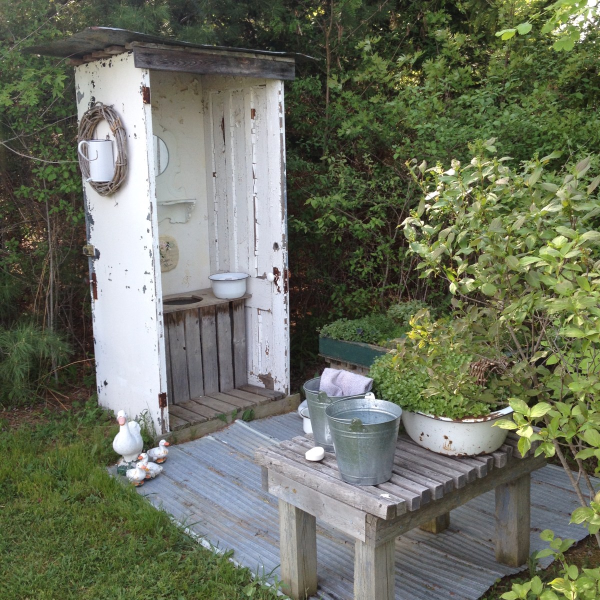 An outdoor lavatory has a basin, decorations but no door.
