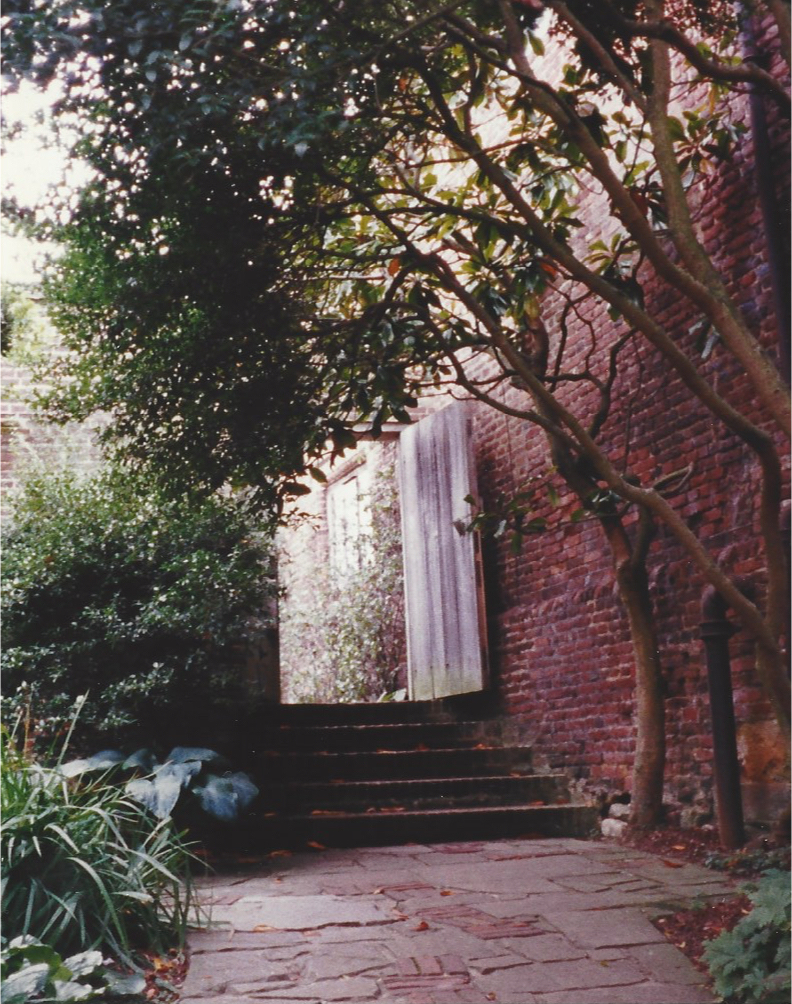 A wooden door in a brick wall between gardens at Sissinghurst