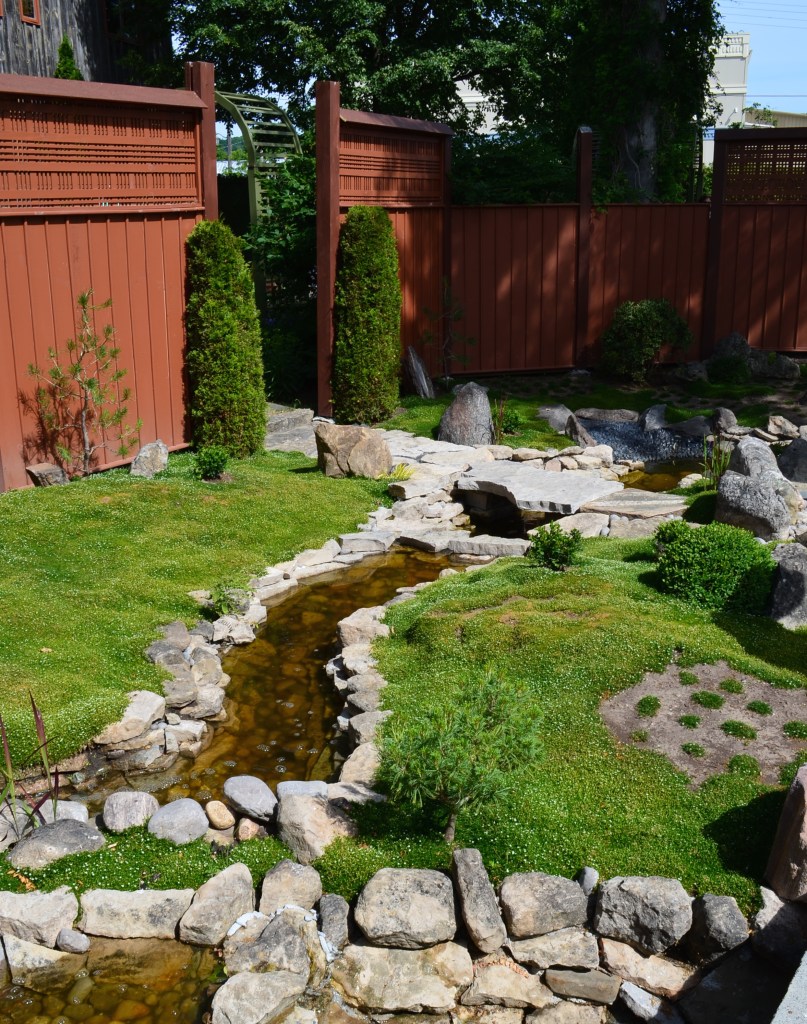 A zen mossy garden with a rock lined brook.