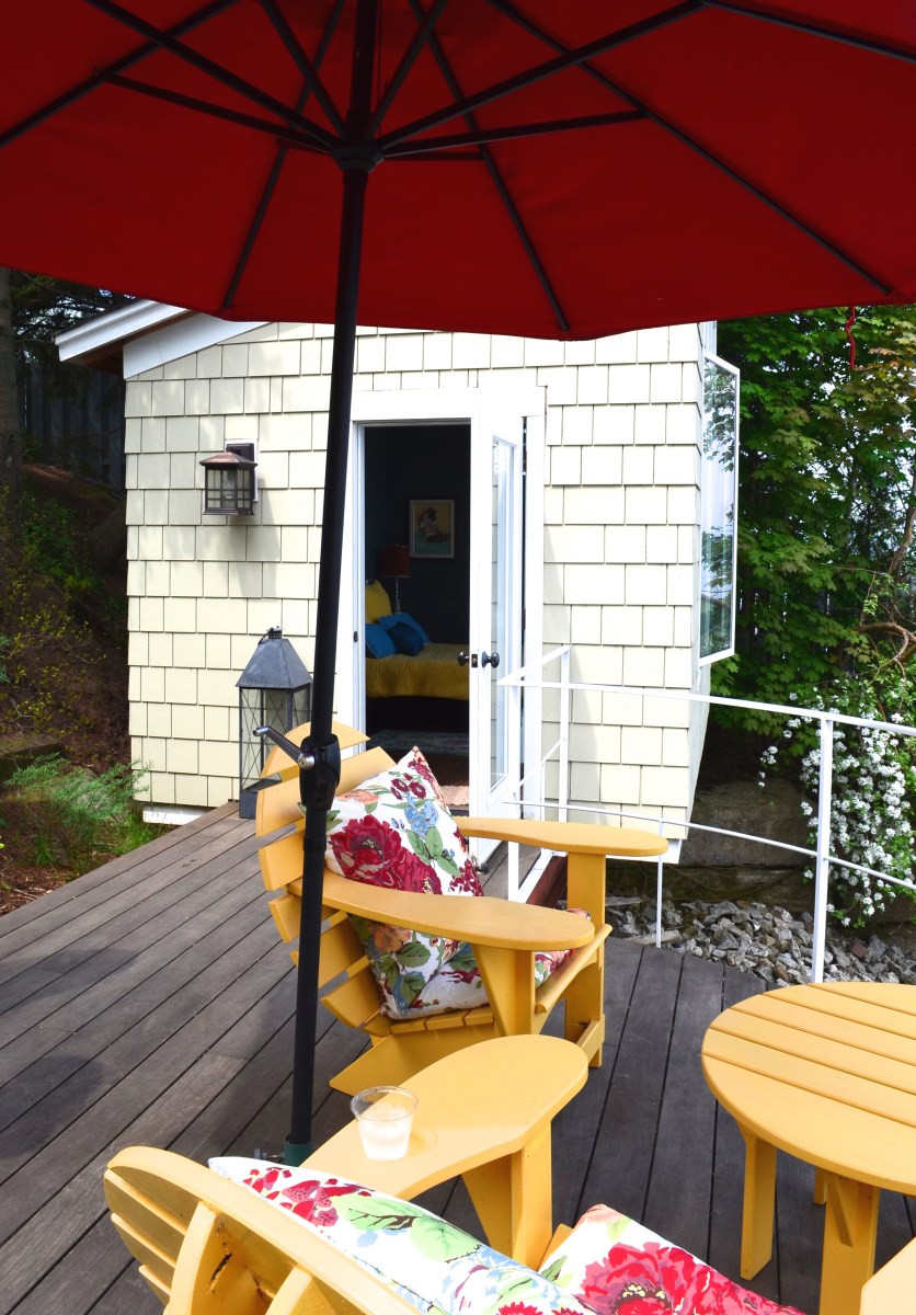 A small bunkie adjacent to a small patio overlooking Lake Ontario.