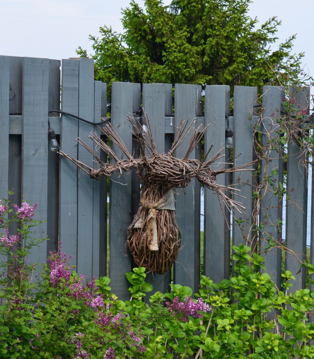 A moosehead made of twigs decorates a fence.