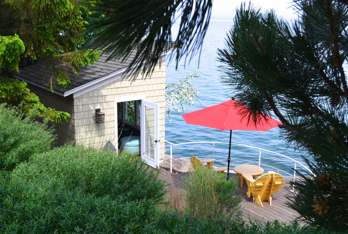 Down a sharp incline, a garden features a patio and bunkie