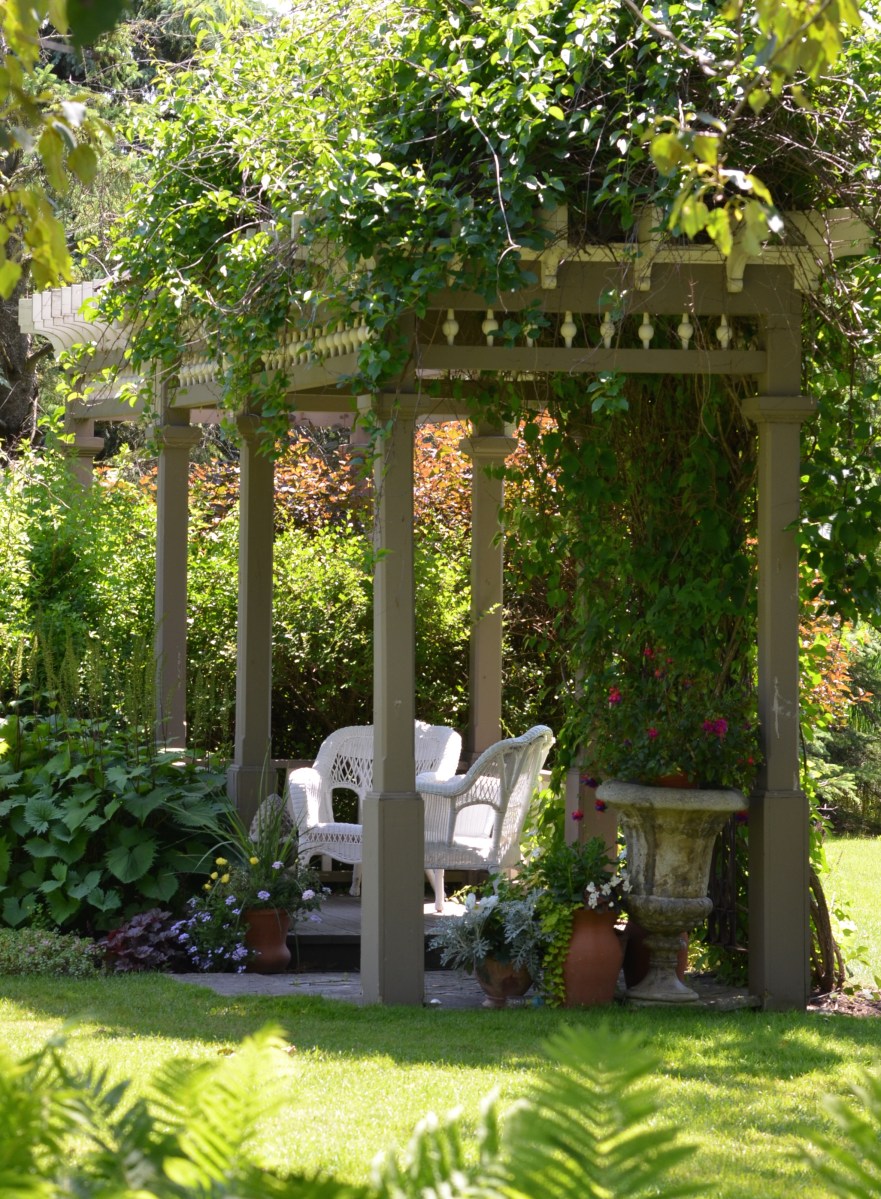 A rectangular gazebo provides shady shelter for garden seating.
