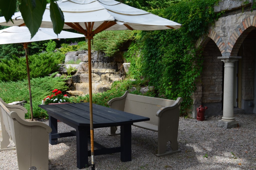 A patio for outdoor dining is situated next to a water feature