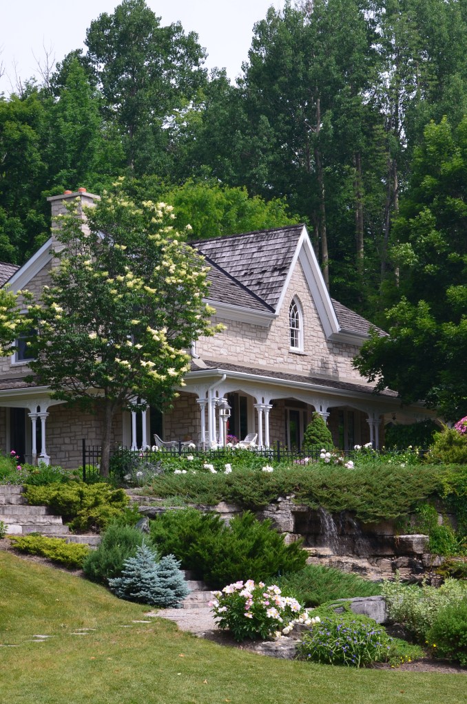 A large country home has a water feature in the front garden on a high slope