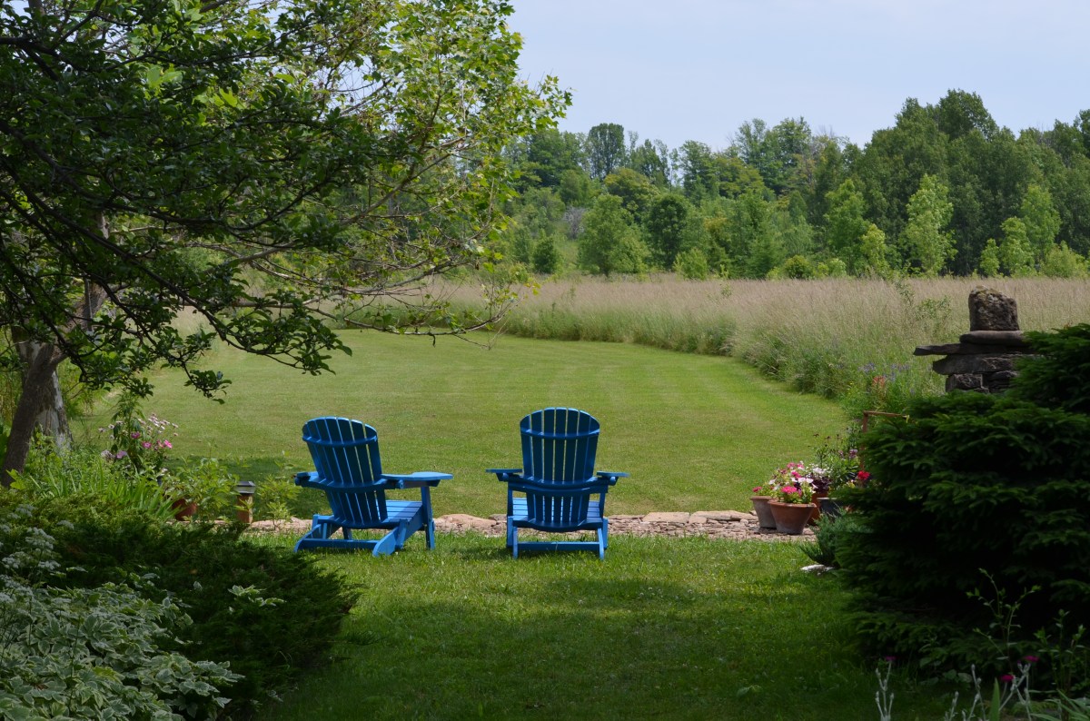 Garden seating overlooking a lawn and field.
