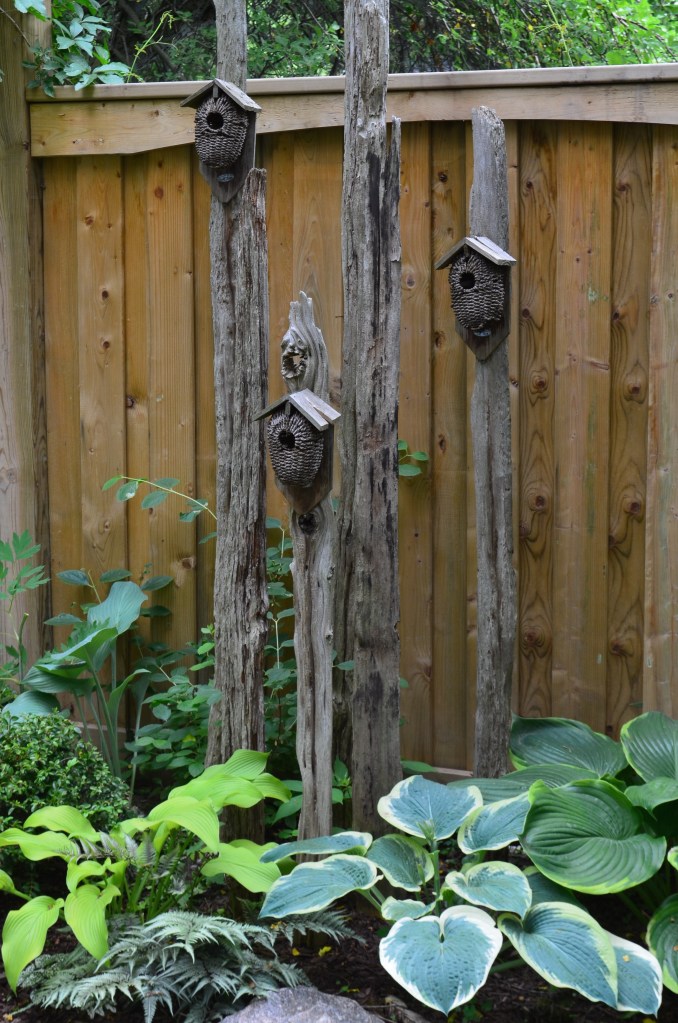 A collection of birdhouses displayed on posts in a small garden
