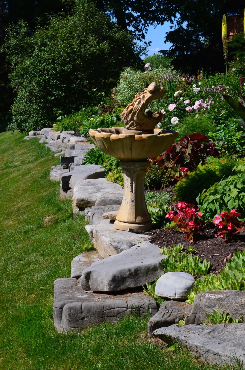Large rocks edge a garden flower bed.