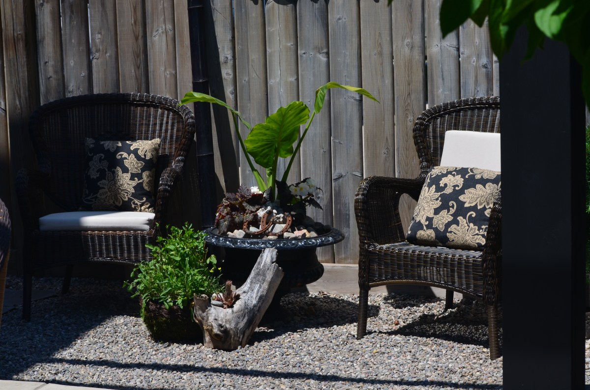 A stylish garden seating area is created in a small area next to a fence.