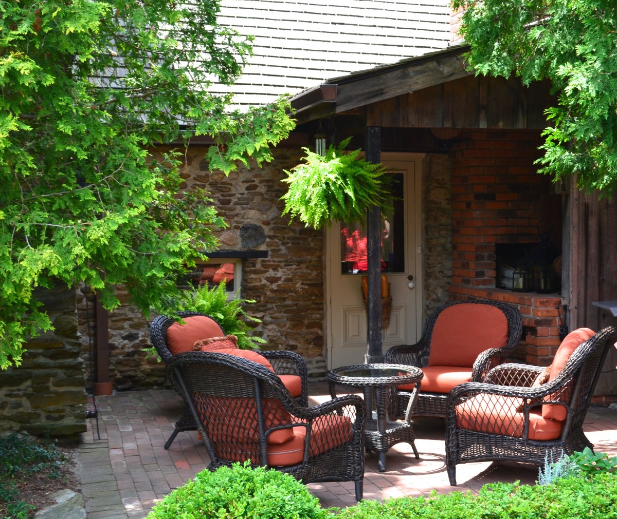 Upholstered chairs offer garden seating in a small patio by the side of a home.