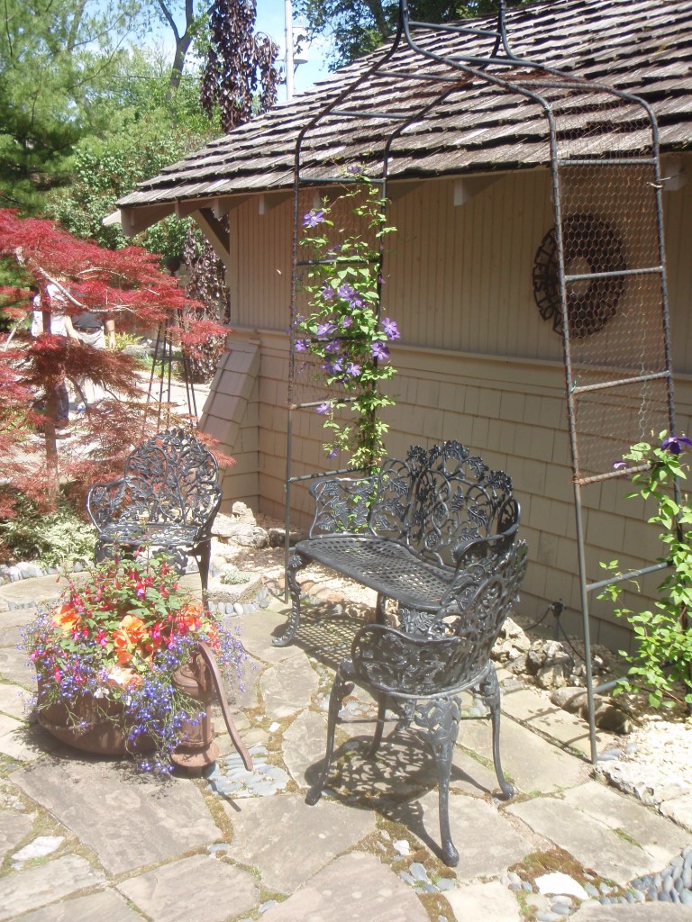 Formal garden seating furnishes a small area between a house and garage.