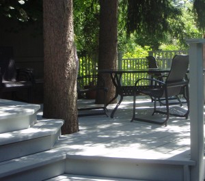 A white painted wooden deck incorporating large trees creates a cooler backyard.
