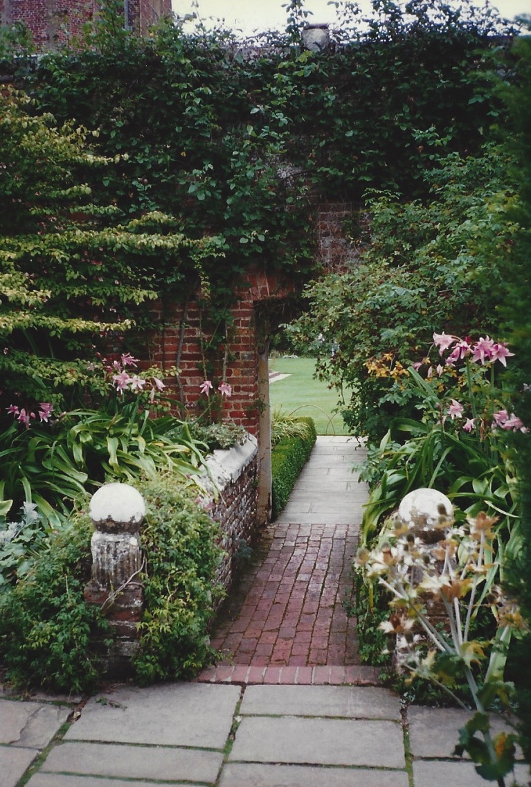 An archway in an old brick wall leads from one garden room to another.