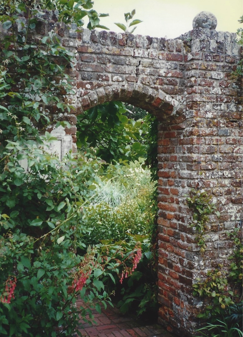 A wall with an entrance leading from one garden room to another.