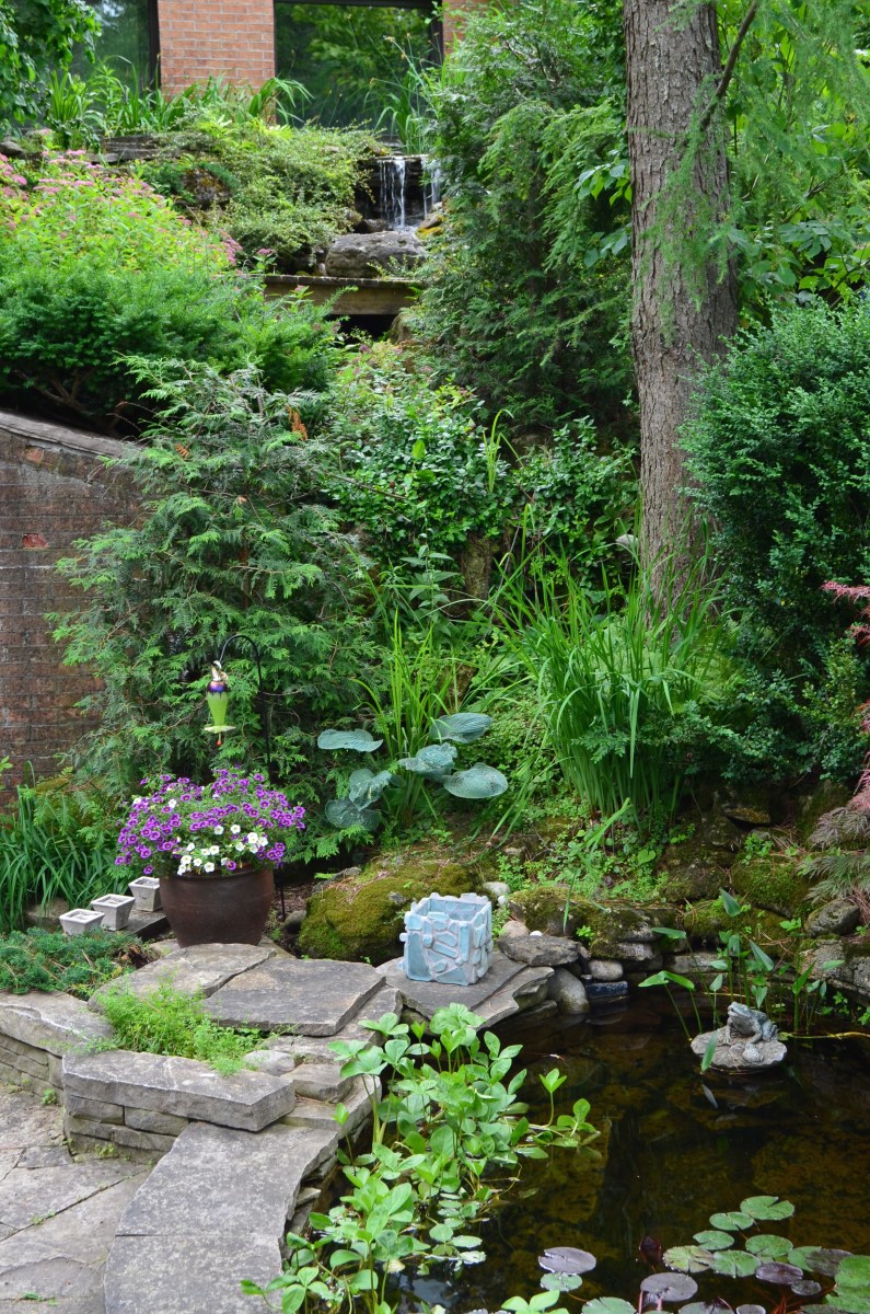 A waterfall, springing from the upper level of the home, flows down to a pond.